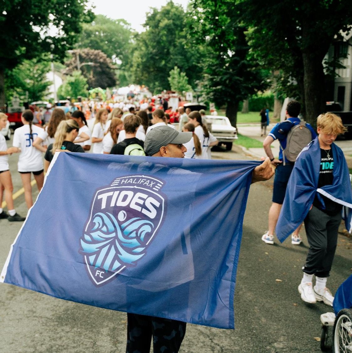 Blue Flag with Halifax Tides FC Crest being held by a fan in the street